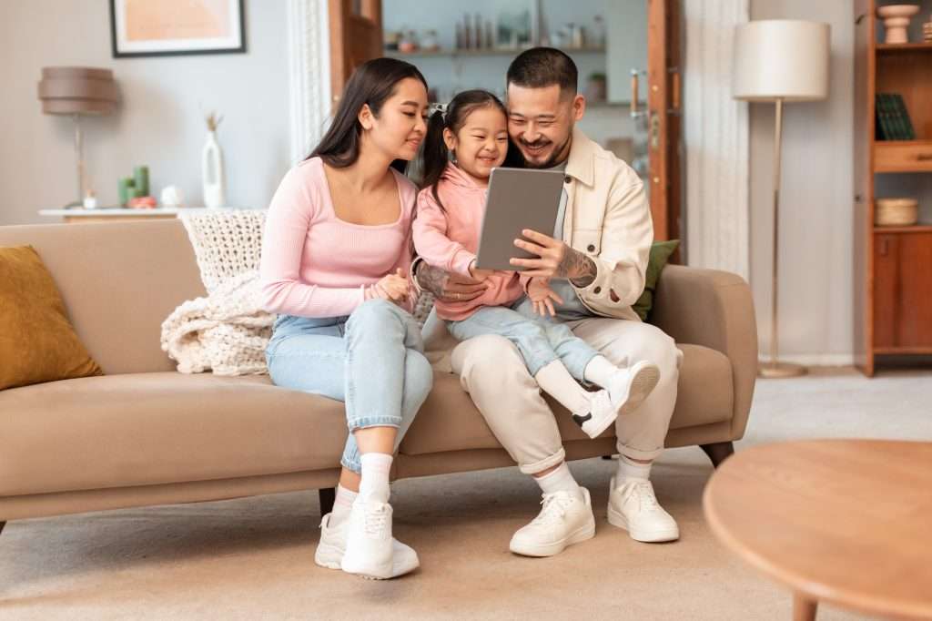 Korean Family Using Tablet Watching Cartoons Online In Living Room